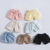 Une collection de mini-shorts en jean roses, jaunes, beige et bleus sont présentés sur un fond blanc.