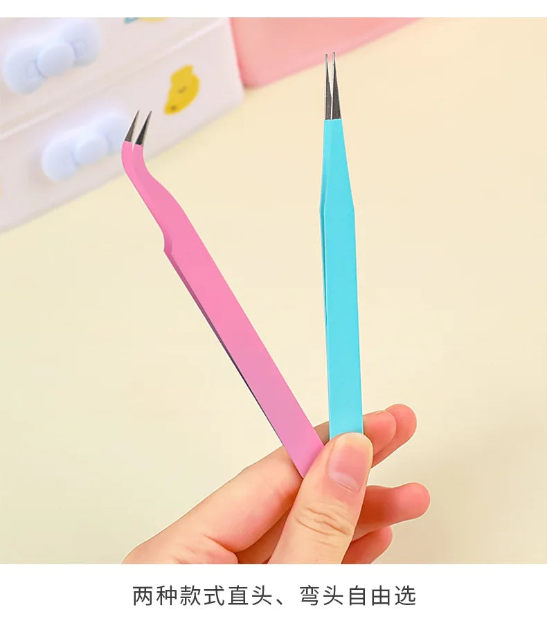 Une main tient un set de pinces de précision rose et bleu à pointes fines sur un fond clair.