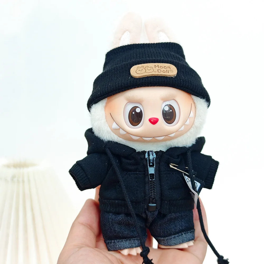 A Labubu doll wearing a black bear hoodie with headphones, held in a hand.
