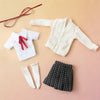 A collection of white and beige knitted clothing items, including a cardigan, a shirt with a red ribbon, and a black plaid sk