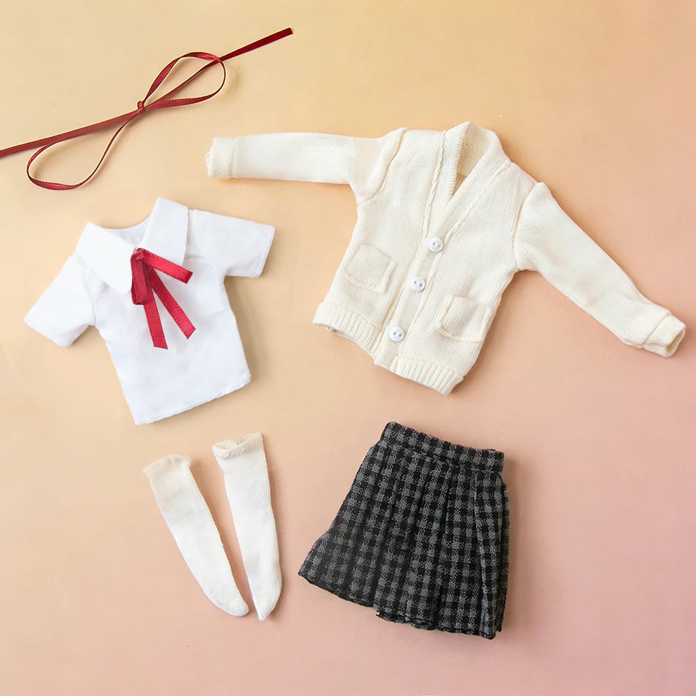 A collection of white and beige knitted clothing items, including a cardigan, a shirt with a red ribbon, and a black plaid sk