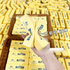 A hand holds a yellow butter squishy fidget toy surrounded by many similar yellow butter toys.