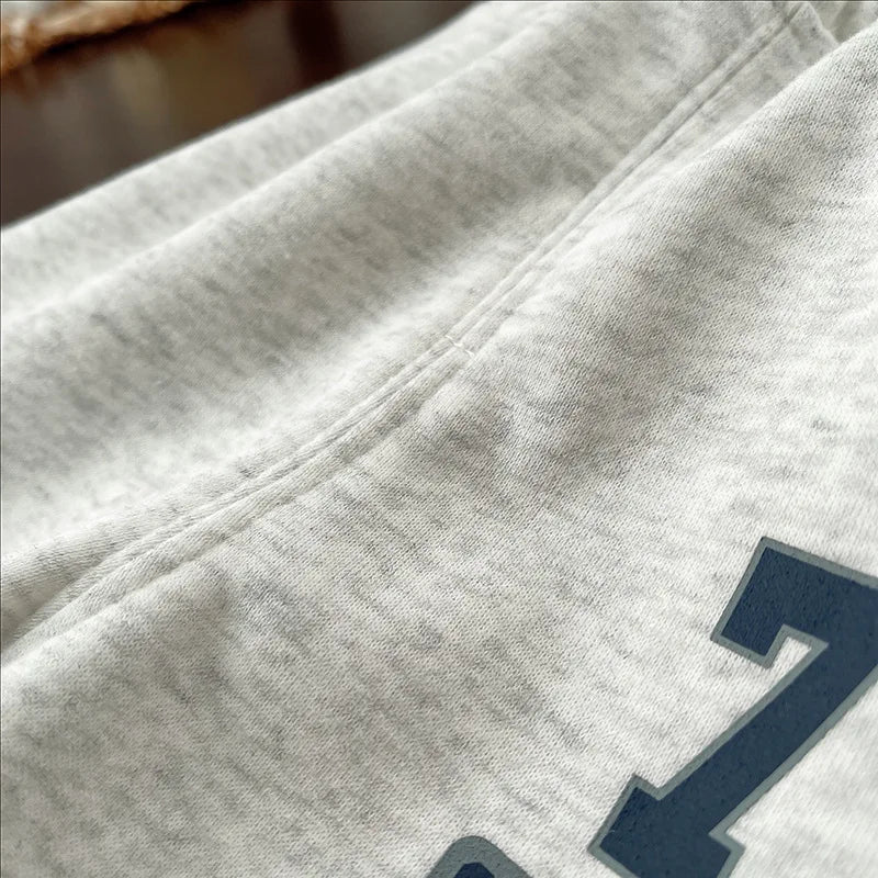 A close-up of a light gray kids' 2-piece long-sleeve sweater and sweatpants set.