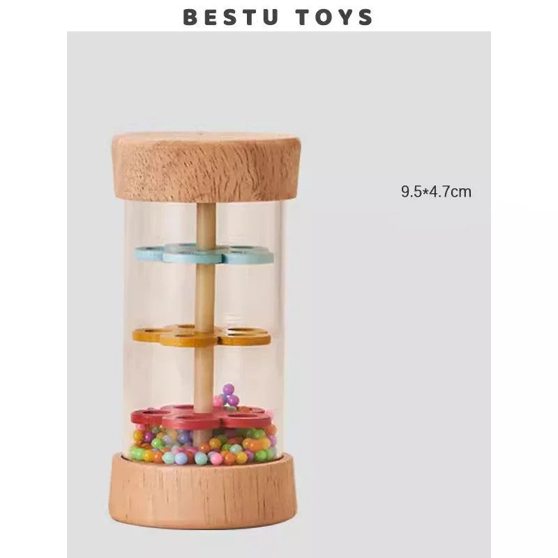 A clear glass jar filled with colorful beads and a wooden top, used as a rain sound shaker toy.