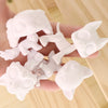 A hand holds several white, customizable bobble head pet figures for a DIY kit.