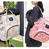 A pink cartoon print waterproof diaper bag being held by a woman in a striped shirt.