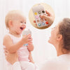 A smiling baby is shown interacting with a woman while holding a food grade silicone baby teether toy.