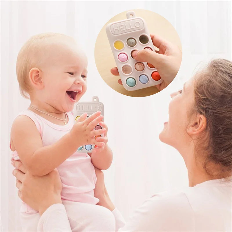 A smiling baby is shown interacting with a woman while holding a food grade silicone baby teether toy.