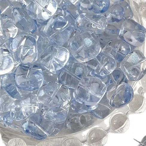 A close-up view of clear blue geometric glass beads in irregular square shapes for jewelry making