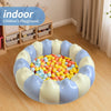 A round inflatable toddler pool filled with colorful plastic balls on a wooden floor.