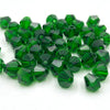 A pile of faceted green bicone crystal glass beads for jewelry making.