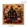 A framed piece of art depicting a spooky Halloween scene with a black house, bats, pumpkins, and glowing lights.