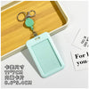 A light mint green retractable ID badge holder with a clip and keychain is displayed on a wooden tray.
