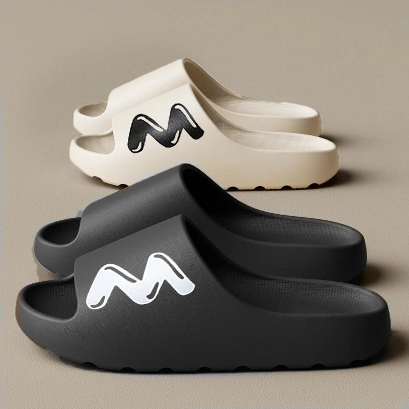 A pair of gray EVA slide slippers with a black zigzag logo on the top