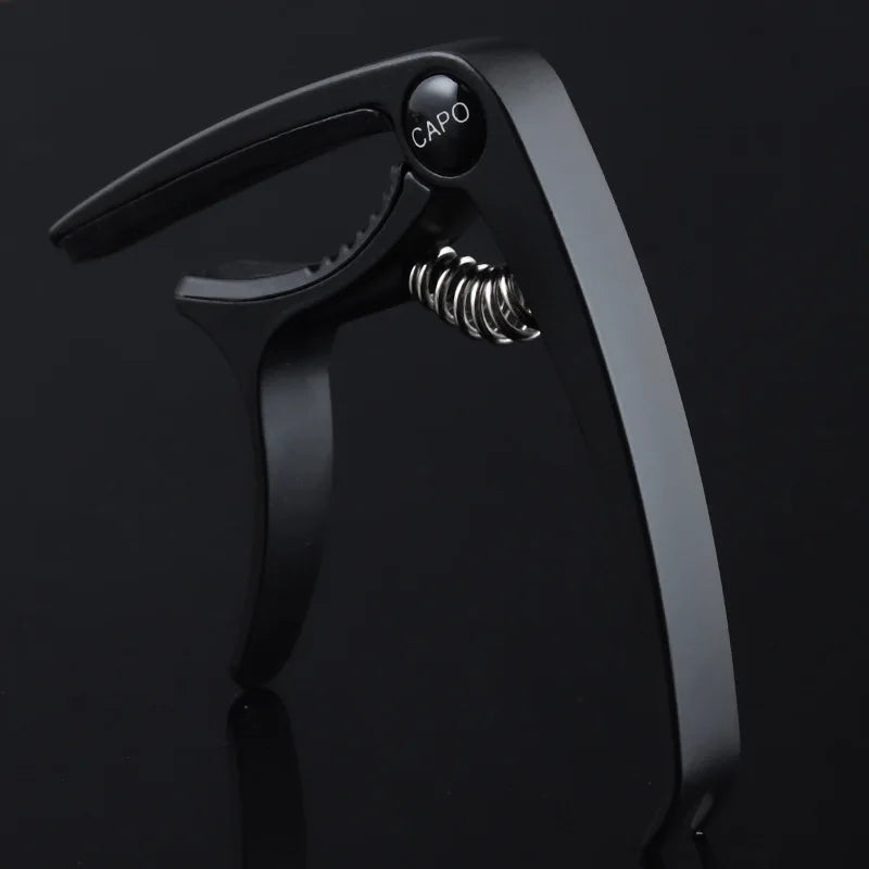 A black aluminum alloy quick-change guitar capo with a visible spring mechanism.