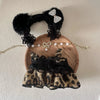 A leopard print sling dress for plush dolls featuring black lace and a sparkly bow accessory.