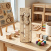 A wooden Montessori busy board for toddlers featuring gears, switches, and sensory elements displayed on a light wood table.