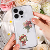 A clear phone case featuring a floral design of pink and red roses, held by a person against a background of white and cream 