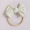 A light beige fabric bow headband with a soft elastic band, suitable for a baby or girl.