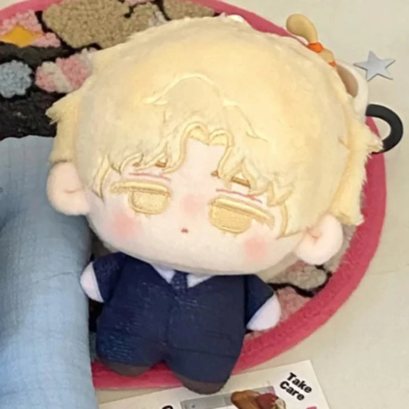 A light blonde plush keychain featuring a character with pale skin and light hair wearing a dark blue outfit.