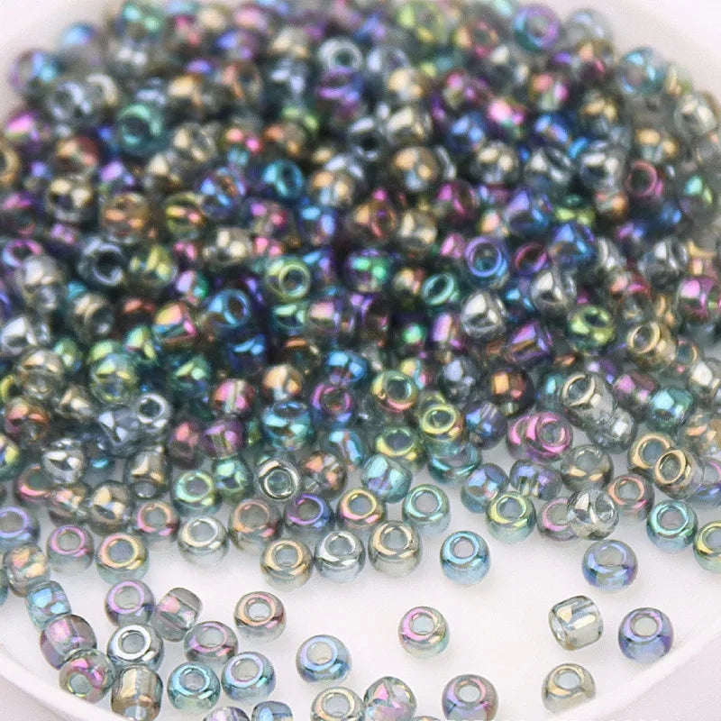 A pile of multicolored glass rice beads in various sizes for DIY jewelry and crafting.