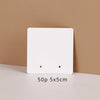 A white square jewelry display card with two holes is shown against a beige background.