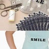 A hand is using a small blue iron-on patch to apply heat transfer to a piece of clothing.