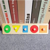 A wooden shape and color sorter puzzle with five colored buttons on a light wood background.