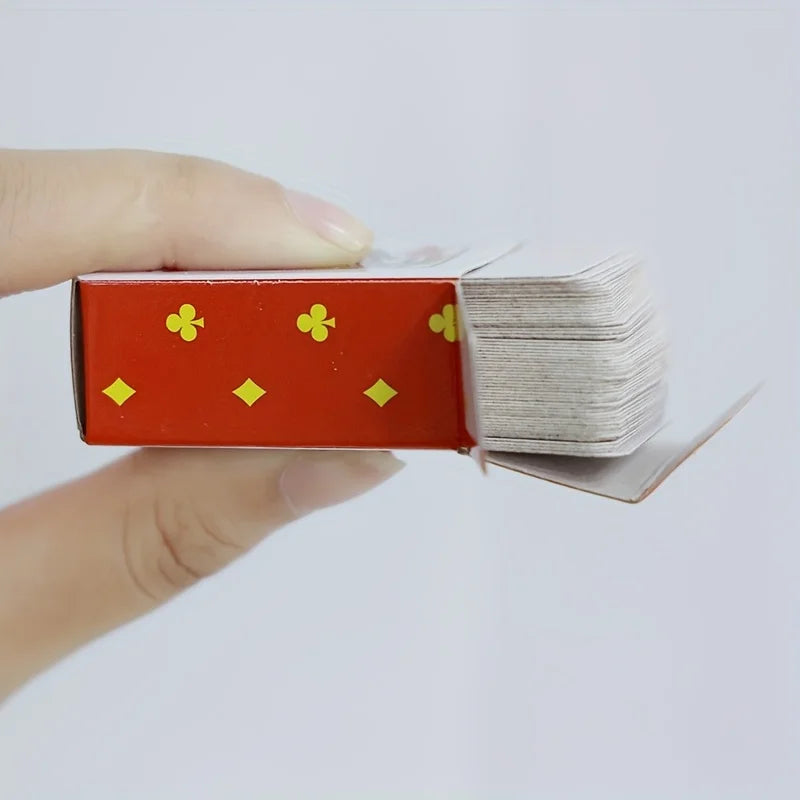 A hand holds a red playing card box with gold symbols, showing a stack of mini cards.