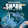 A hand holds a remote control for a blue swimming shark toy, with the shark swimming in the water.
