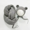 A knitted gray bear hat and wrap set with a round white pom-pom on a white background.
