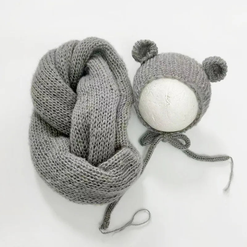 A knitted gray bear hat and wrap set with a round white pom-pom on a white background.