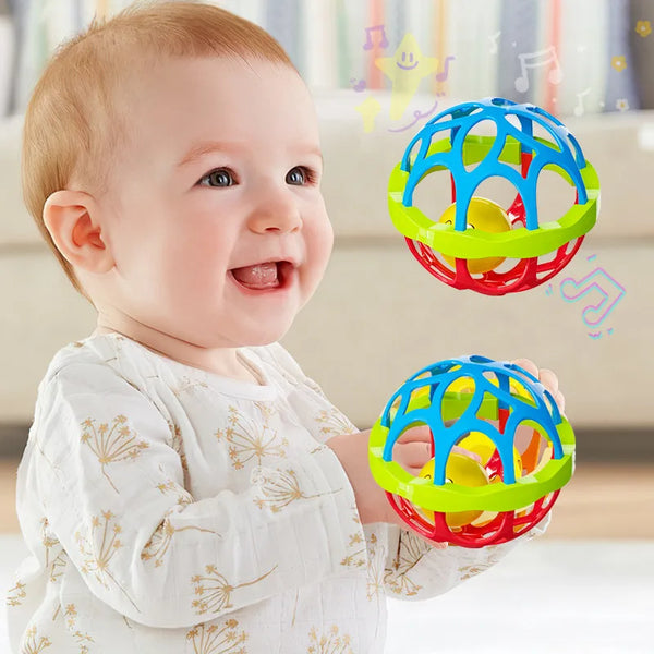 A smiling baby is holding a colorful sensory rattle toy with blue, green, and red rings.