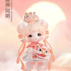A small, pink collectible figurine of a girl with light pink hair and large eyes, dressed in white and orange clothing.