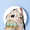 A pink cartoon print waterproof diaper bag with clear bottles and accessories displayed on a white stand.