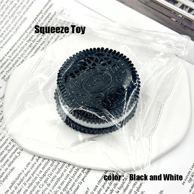 A black and white silicone biscuit squishy stress relief toy resting on a white plate.