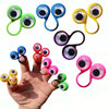 A hand is holding various colorful silicone eye rings, including green, blue, yellow, and purple, for sensory play.