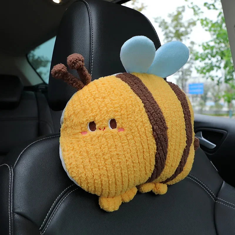A yellow and brown plush animal pillow resembling a bee with blue wings resting on a black car seat.