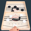 A wooden catapult tabletop hockey game with black and white pieces and a hand placing a piece.
