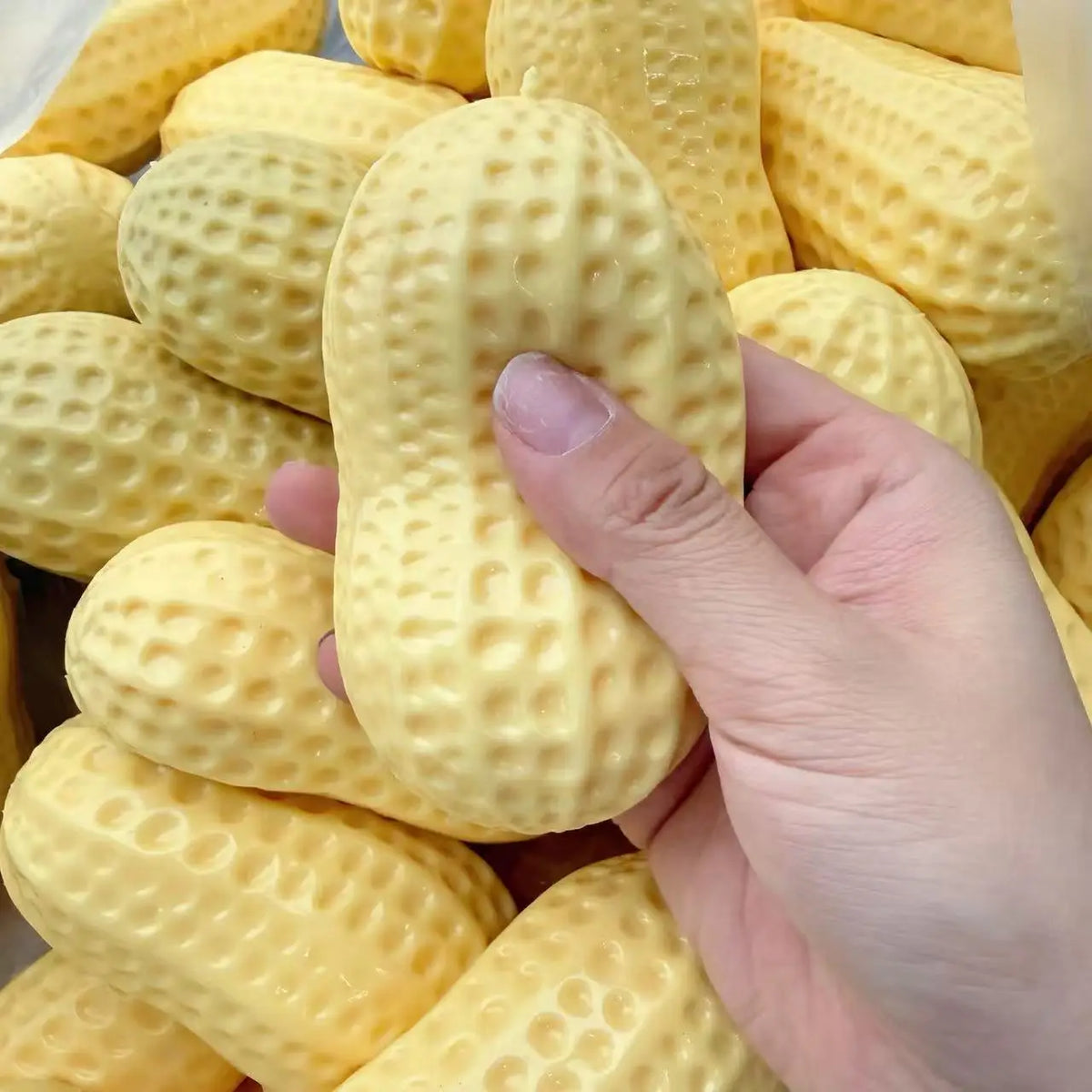 A hand is squeezing a yellow, textured squishy stress ball for anxiety relief.