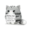 A handmade gray and white crochet cat figurine with a sign that reads You're Purr-fect