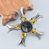 A metal fidget spinner with a silver finish and gold accents, resting on a wooden surface.
