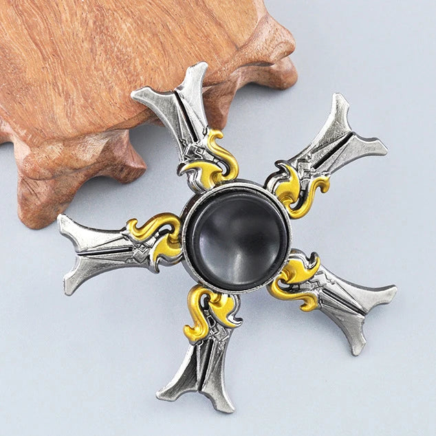 A metal fidget spinner with a silver finish and gold accents, resting on a wooden surface.