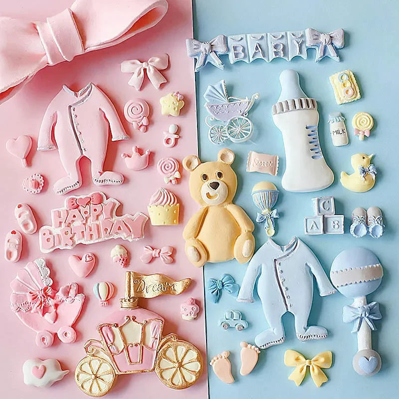 A pink and white baby-themed silicone cake molds set featuring various shapes like a stroller, bottle, pacifier, and teddy be