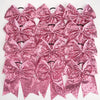 A pack of twelve pink glitter sequin pigtail bows for girls with elastic hair ties.