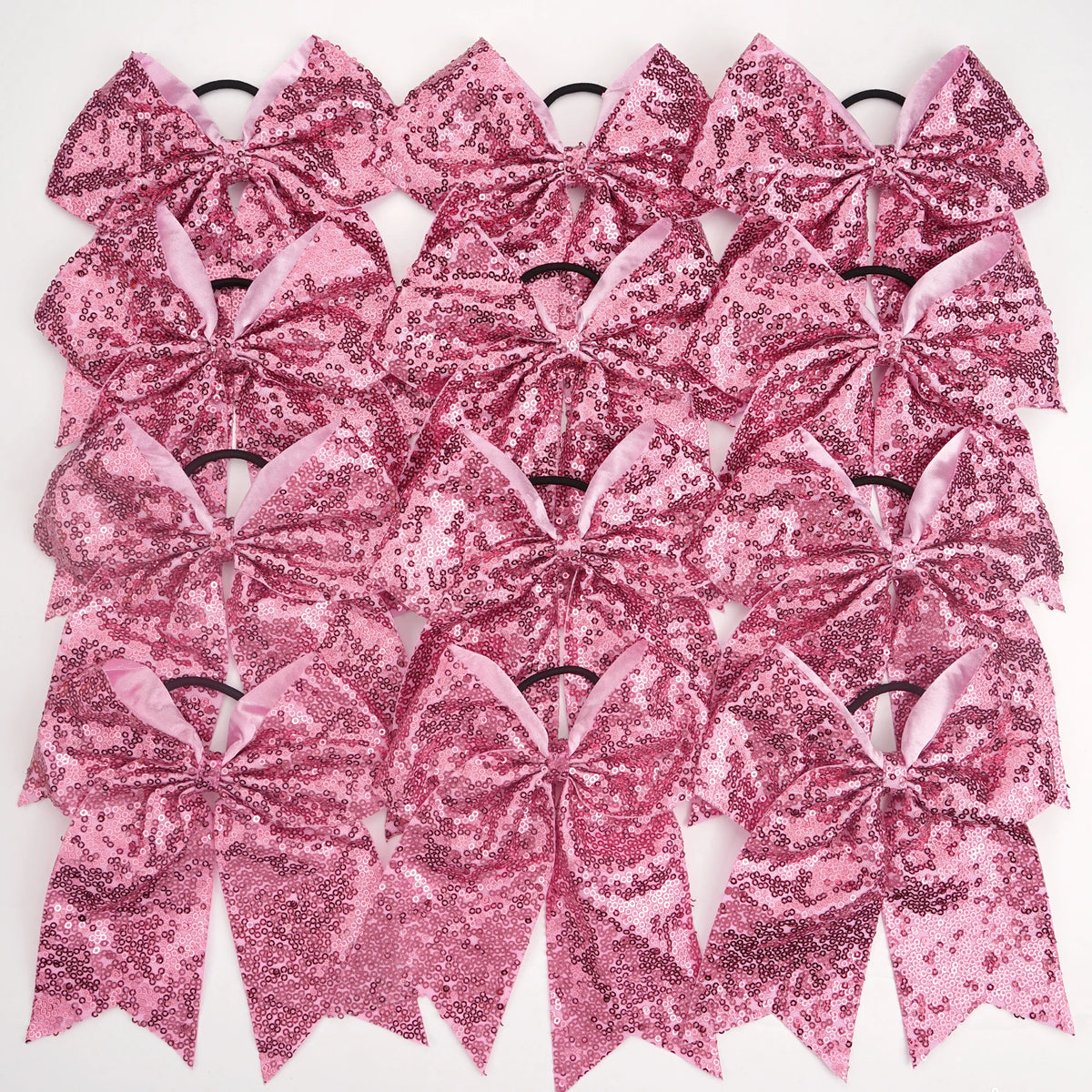A pack of twelve pink glitter sequin pigtail bows for girls with elastic hair ties.