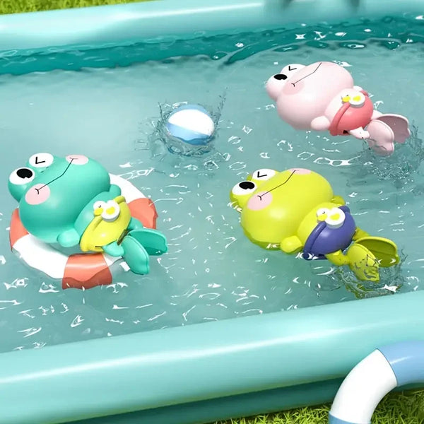 Aufziehbares Spielzeugfrosch in rosa und grün, schwimmend in einer hellblauen Plastikbadewanne.