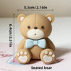 A seated tan bear figure with light blue accents, used as a birthday or baby shower cake topper.