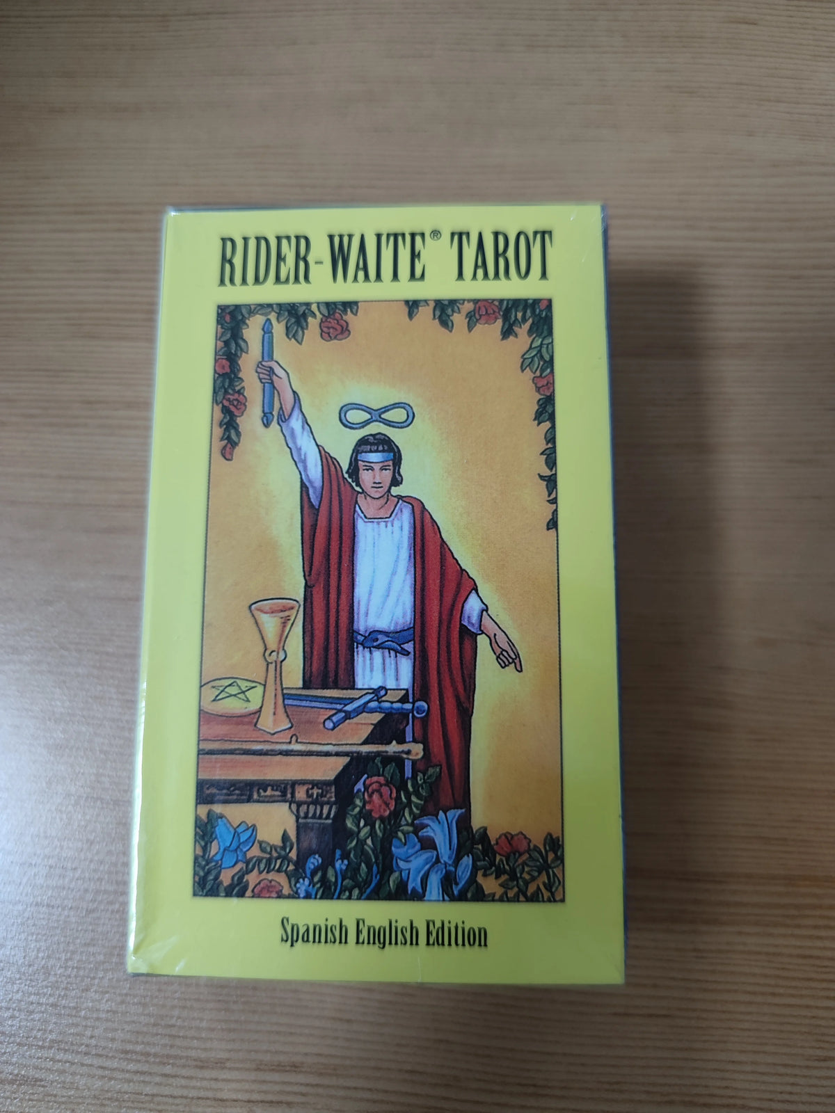 A yellow deck of Rider-Waite Tarot cards with a Spanish English Edition guidebook displayed on a wooden surface.