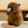 A brown capybara plush toy with light blue eyes sitting on a woven mat.